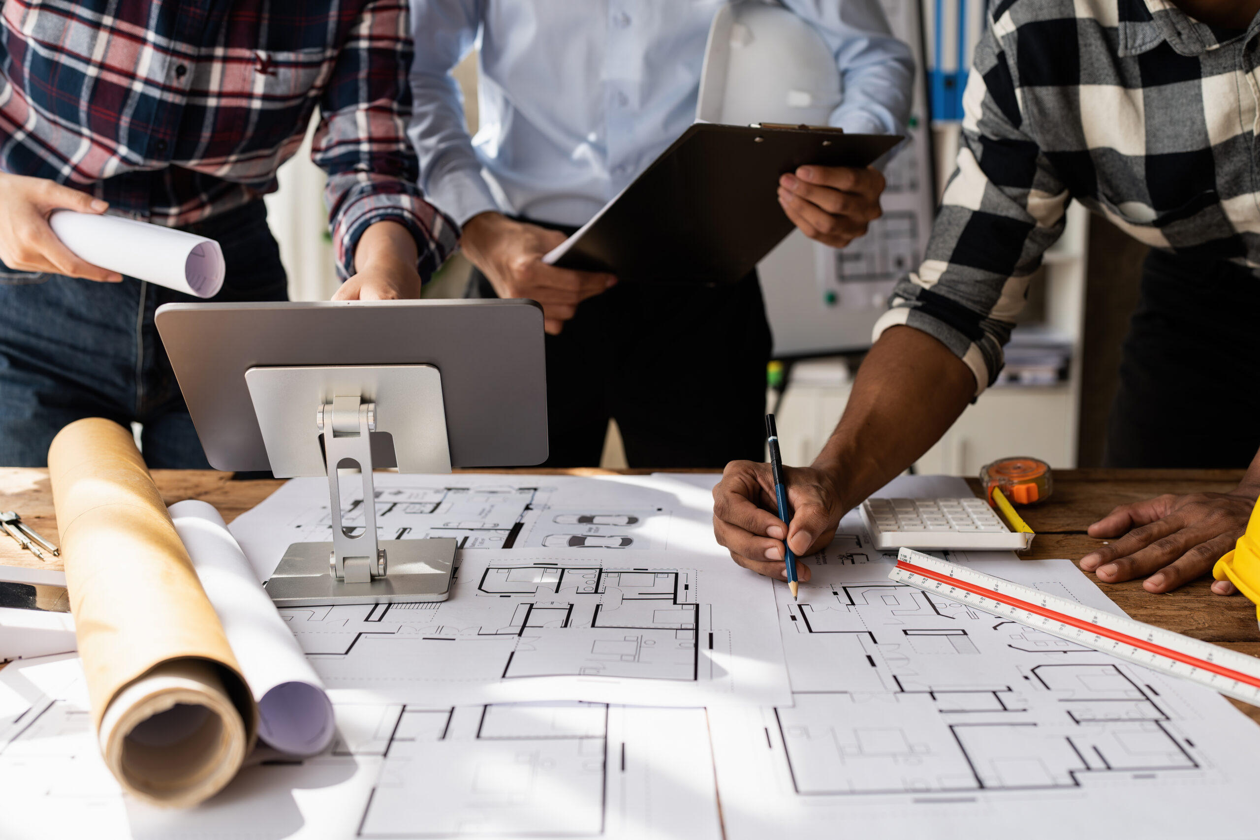 Architect team working with blueprints for architectural plan, engineer sketching a construction project, green energy concept